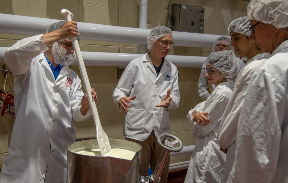 A group in white lab coats attending a dairy product demonstration.